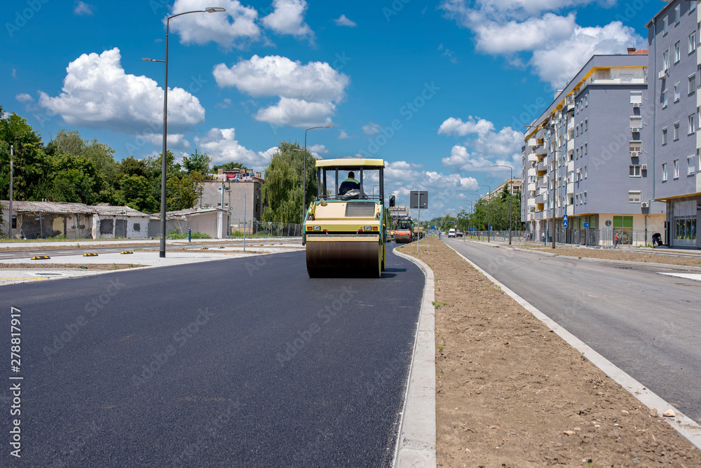 Asphalt roller compactor on site, compacting new asphalt pavement in urban modern city