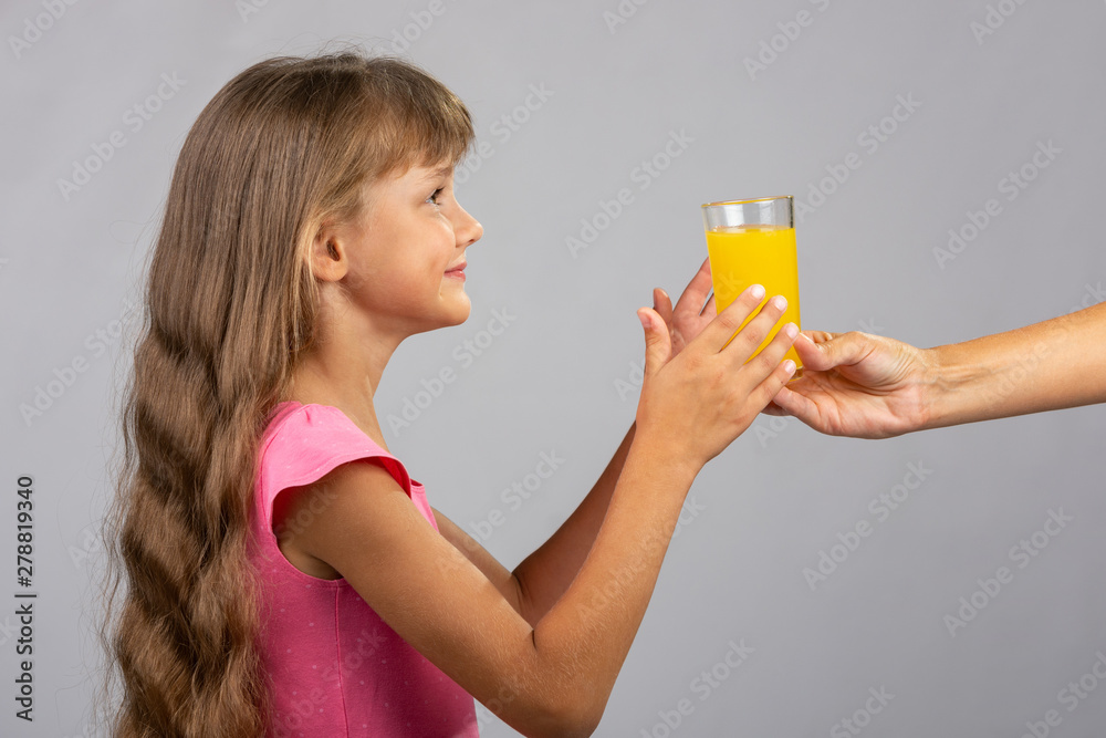The hand holds out a glass of orange juice The hand holds out a glass of orange juice