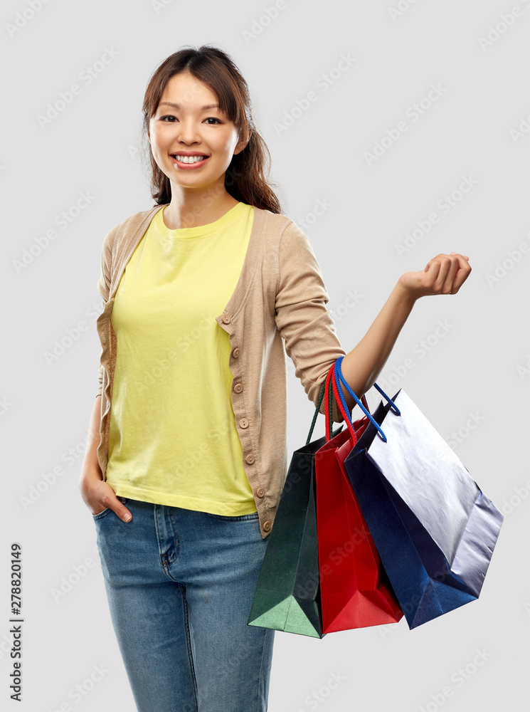 sale, outlet and consumerism concept - happy asian young woman with shopping bags over grey background sale, outlet and consumerism concept - happy asian young woman with shopping bags over grey background