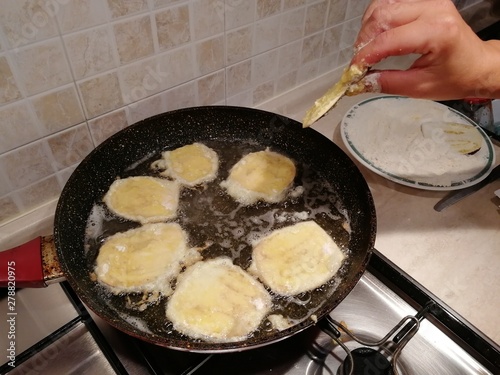 Woman's hand frying eggplant slices to prepear italian traditional food called Parmigiana  photo