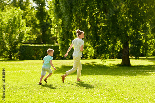 family  leisure and people concept - happy mother and little son running and playing catch game at summer park