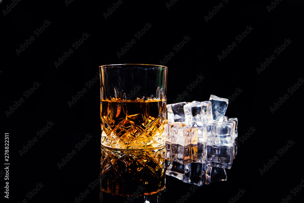 whiskey with ice cubes on black background