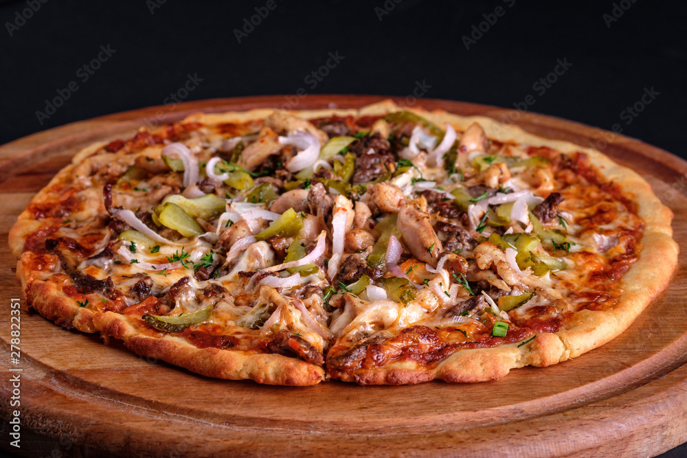 Gluten Free BBQ Chicken Pizza with lots of vegetable fillings, pickles and meat slices on a wooden board.