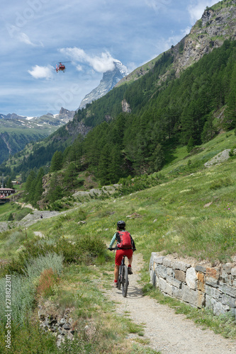 active senior woman, riding her electric mountainbike below the famous Matterhorn in Zermatt, Wallis,Switzerland