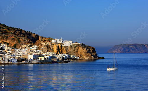 Yacht leaving Mandraki villlage, "capital" of Nisyros volcanic island, Dodecanese, Greece. On the rock above the village you can see the Monastery of Panagia Spiliani 
