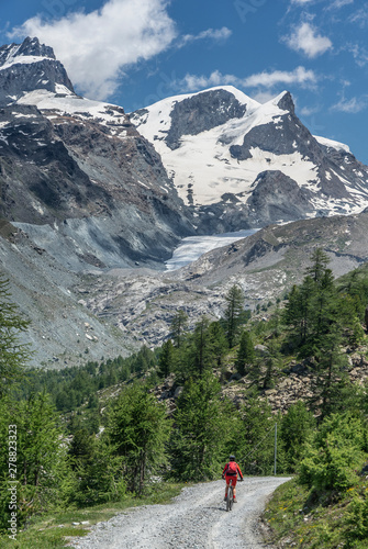 active senior woman, riding her electric mountainbike below the famous Gornergrat in Zermatt, in the background Rimpfischhorn and Strahlhorn,Wallis,Switzerland