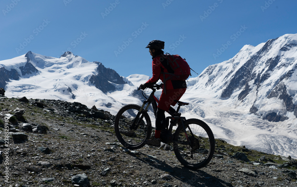 active senior woman, riding her electric mountainbikeon the Gornergrat in Zermatt, Wallis,Switzerland. In The background Gorner Glacier, Monte Rosa, Liskam am Breithorn active senior woman, riding her electric mountainbikeon the Gornergrat in Zermatt, Wallis,Switzerland. In The background Gorner Glacier, Monte Rosa, Liskam am Breithorn