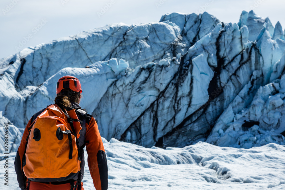 Man with waterproof pack walking toward the icefall of the Matanuska Glacier in the Chugach Mountains.