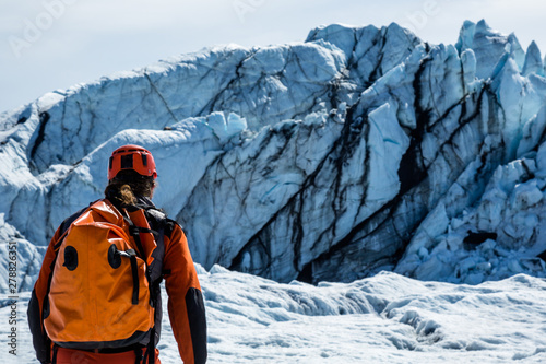 Man with waterproof pack walking toward the icefall of the Matanuska Glacier in the Chugach Mountains.