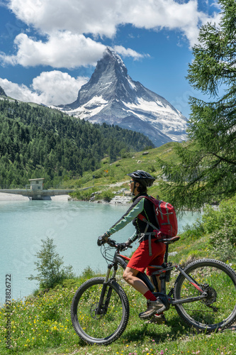 active senior woman, riding her electric mountainbike below the famous Matterhorn in Zermatt, Wallis,Switzerland