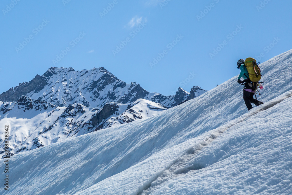 Female ice climbing guide walking below Mt Wickersham on the Matanuska Glacier in Alaska.
