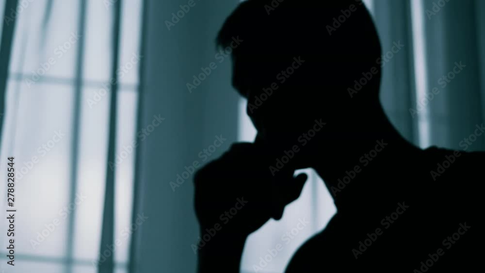 Anonymous blurred silhouette of a man talking on a cell phone in a dark room, a criminal is extorting money Anonymous blurred silhouette of a man talking on a cell phone in a dark room, a criminal is extorting money