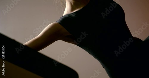 Close-up of the body of a sports girl, she is engaged in Pilates, doing exercises on the side bar with the help of a simulator.