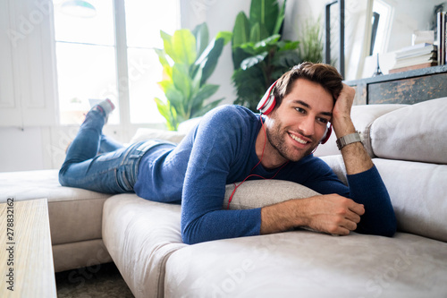 Relaxed man lying on couch listening to music