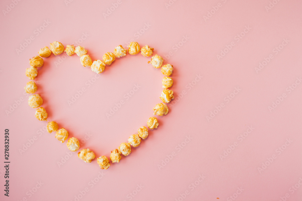 Love movies, concept on a pink background. Popcorn scattered on pink background heart shaped Love movies, concept on a pink background. Popcorn scattered on pink background heart shaped
