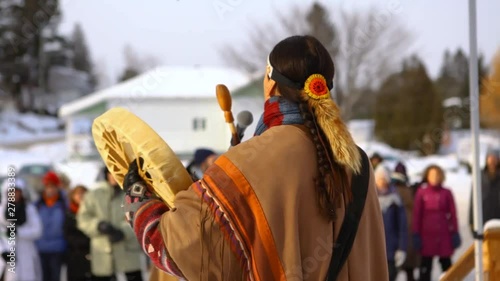 Environmentalists stage demonstration. A Native American plays music on a traditional drum, viewed from behind, during an outdoor gathering held by environmental campaigners.
