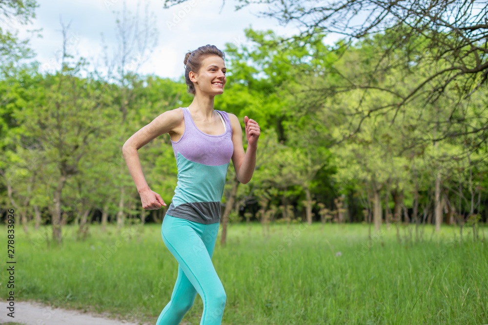Sports brunette girl jogging in the park. Green forest on the background Sports brunette girl jogging in the park. Green forest on the background