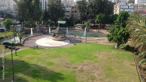 Drone rises above a beautiful gazebo in the park with pigeons on the background of fountains