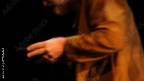 Traditional folk music played in bar. An elderly man is viewed from behind playing an old-fashioned thumb piano during an intimate performance inside a local club. photo