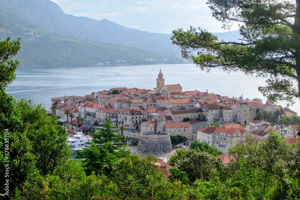 A view from afar looking down through the trees from a lookout of the beautiful ancient Croatian town of Korcula, on Korcula Island in the Adriatic sea off the coast of Croatia