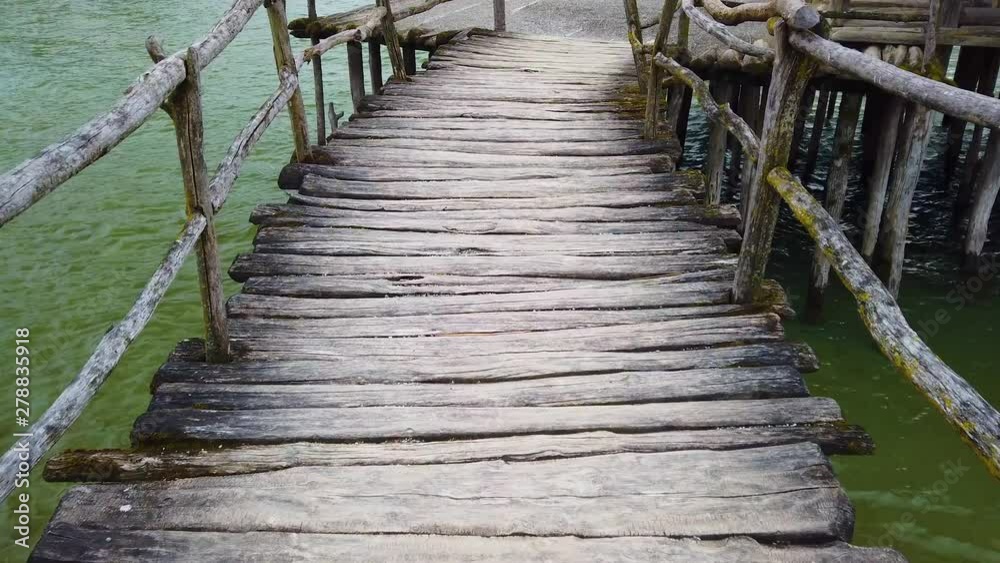 4K video of Old wooden footbridge over water. The camera goes slowly across the bridge. Below it is the clear waters of Lake Constance. 4K video of Old wooden footbridge over water. The camera goes slowly across the bridge. Below it is the clear waters of Lake Constance.