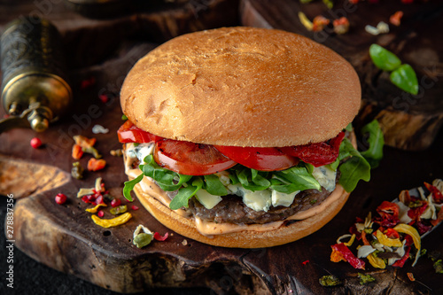 Tasty grilled burger with beef, dorblu cheese and feta and vegetables  Delicious grilled gourmet cheeseburger on a dark background. Free space for text photo