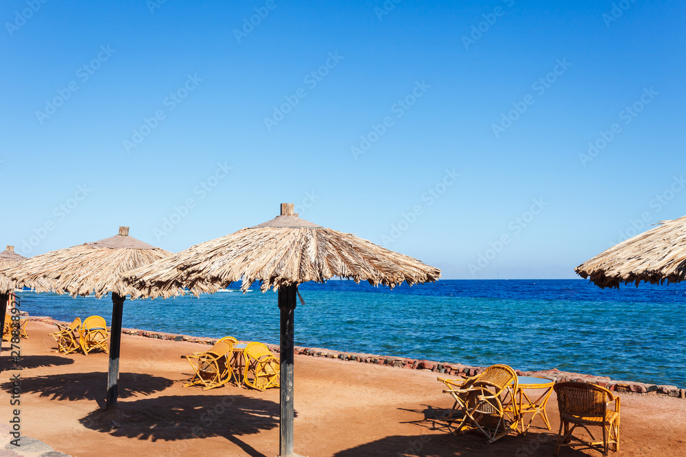 Sunny resort beach at the coast shore of Red Sea in Dahab, Sinai, Egypt, Asia in summer hot. Famous tourist destination near of Sharm el Sheikh. Bright sunny light
