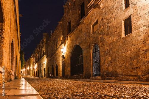Night photo of ancient street of the Knights in Rhodes city on Rhodes island, Dodecanese, Greece. Stone walls and bright night lights. Famous tourist destination in South Europe