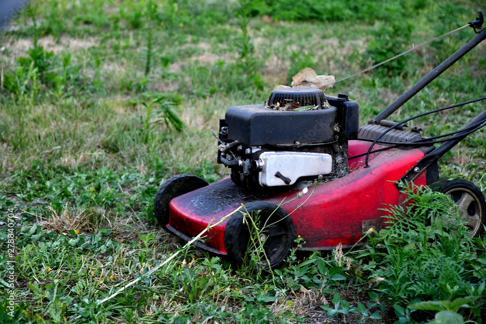 Very old gasoline mower works in the garden in summer. Very old gasoline mower works in the garden in summer.