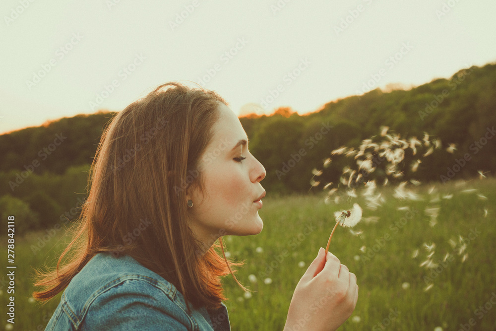 Profile of teenage girl blowing dandelion Profile of teenage girl blowing dandelion