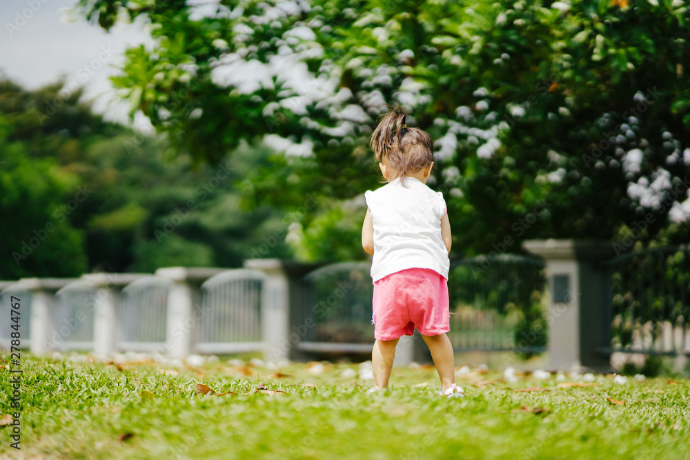 Asian toddler girl running in the park at the spring or summer day.