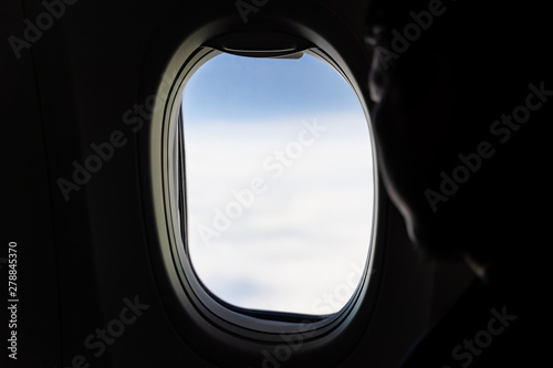 Aerial view of white clouds from airplane window with silhouette man face look outside