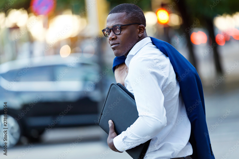 Young businessman with blue suit jacket over his shoulder and laptop bag  Stock-Foto | Adobe Stock