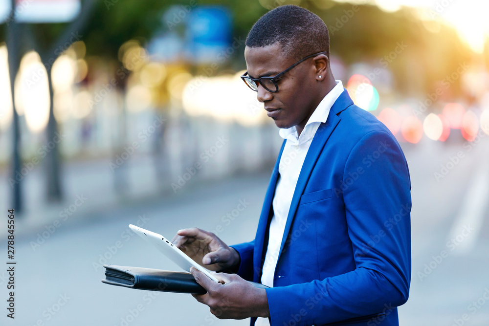 Young businessman wearing blue suit jacket and using his digital tablet at a street Young businessman wearing blue suit jacket and using his digital tablet at a street