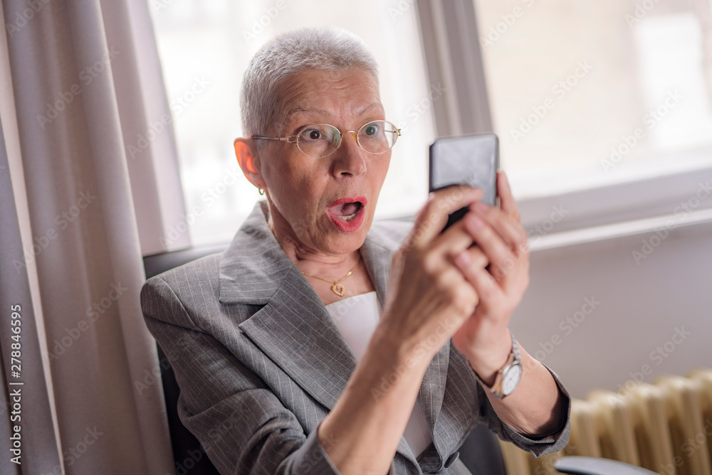 Shocked senior woman looking at her phone Shocked senior woman looking at her phone