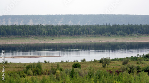North of Vilyuy river in Yakutia in autumn flowing in a wild impassable spruce tundra near the shores of the chalk hills of different heights on the horizon.