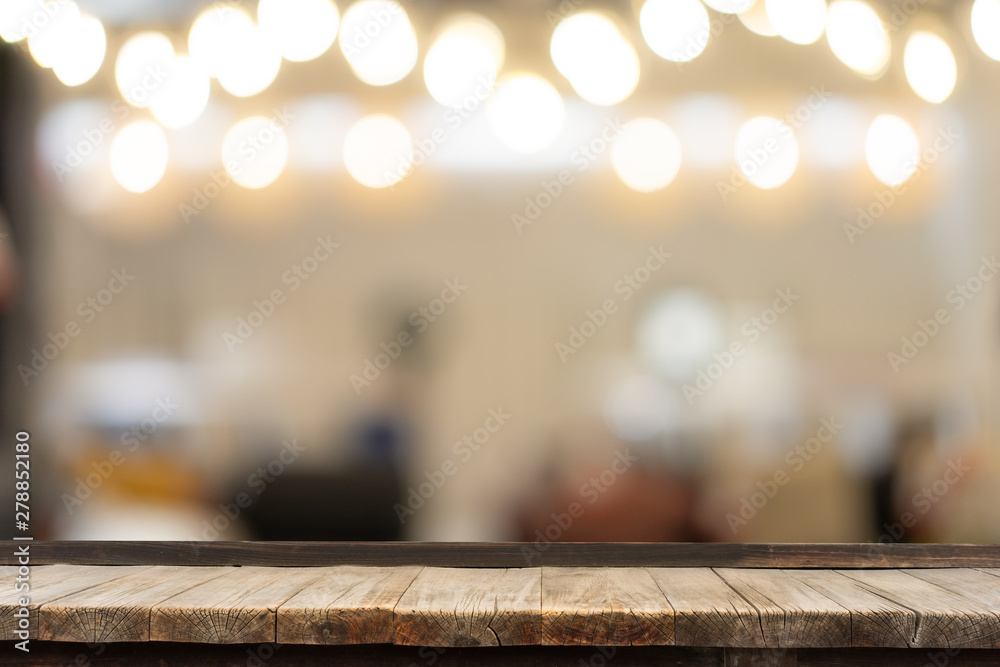 Selective focus of wooden table in front of decorative indoor string lights. Christmas, festival and holiday concepts, can used for display or montage your product