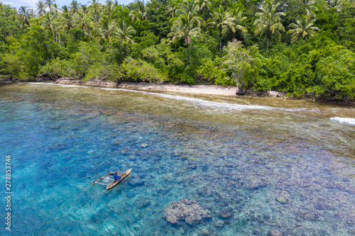 A villager paddles his outrigger canoe in the warm, blue waters surrounding the island of New Britain in Papua New Guinea. This area is part of the Coral Triangle due to its high marine biodiversity.
