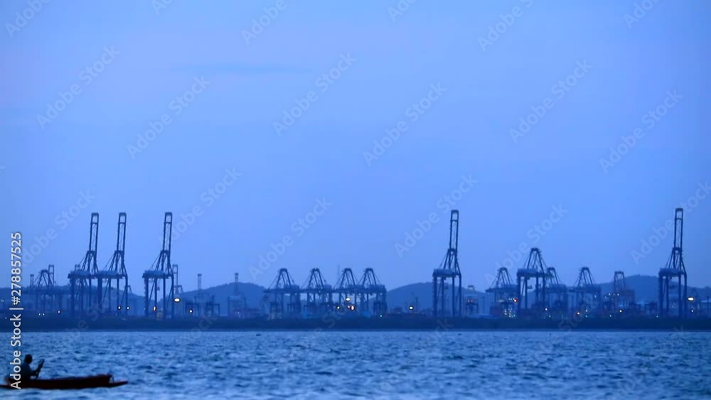 Fishermen rowed back from the fish in twilight time and crane in seaport background Fishermen rowed back from the fish in twilight time and crane in seaport background