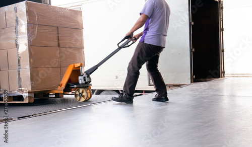 Workers Using Hand Pallet Jack Unloading Package Boxes into Cargo Container. Delivery Shipment Boxes. Trucks Loading at Dock Warehouse. Supply Chain. Warehouse Shipping Transport and Logistics. 