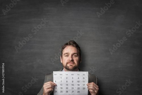 Businessman showing paper calendard in front of him