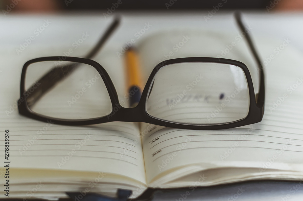 black glasses lie on the book on the table, rest in the process of education