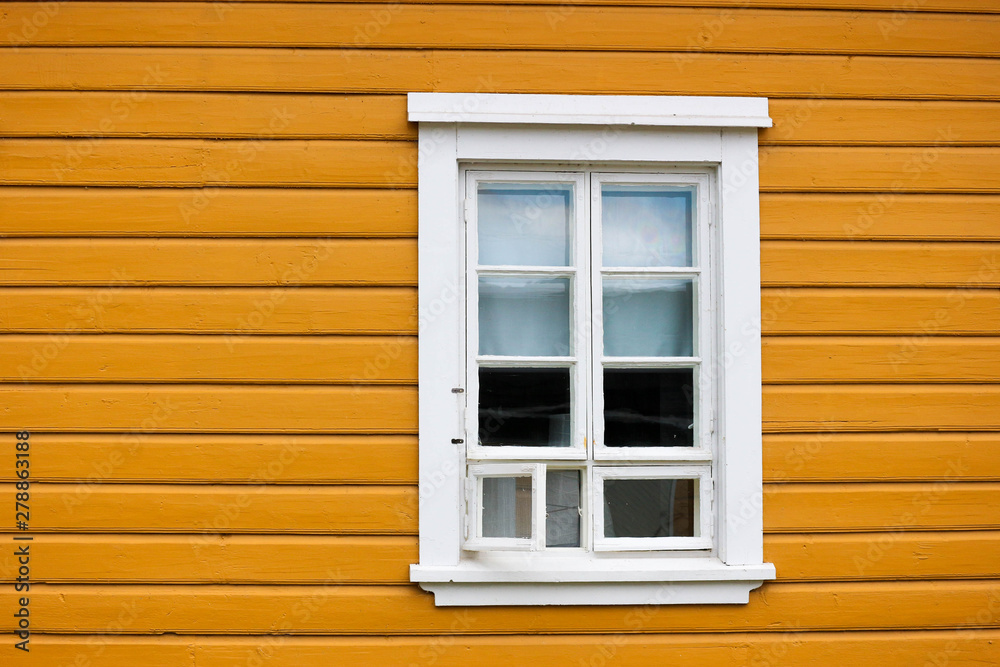 old white wooden window with shutters on the yellow wall