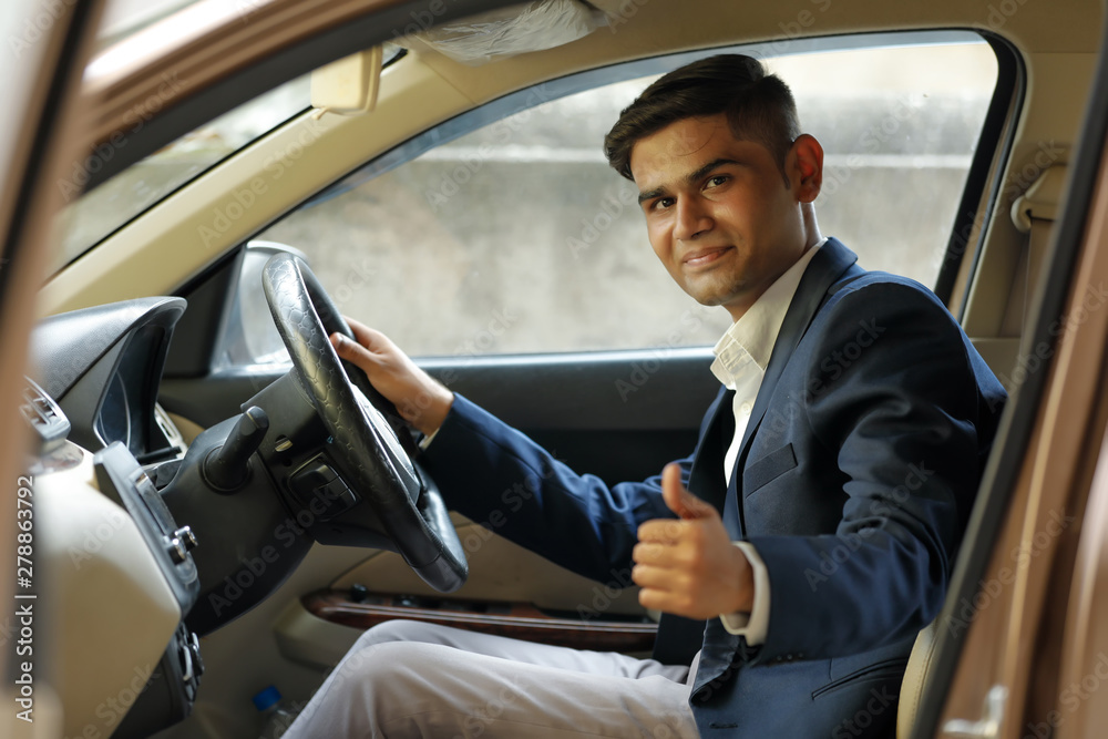 young indian man showing thumps up from car window