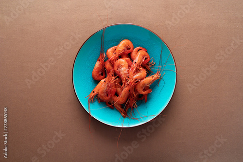 From above ready appetizing prawn in blue plate on brown background photo