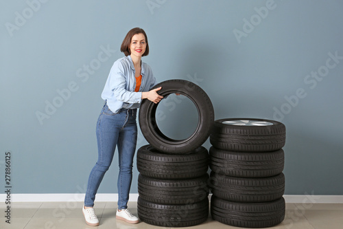 Young woman with car tires near color wall