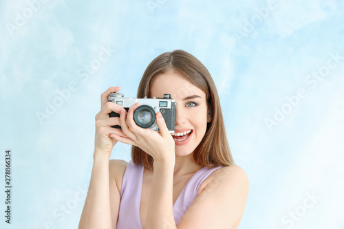 Young female photographer on color background © Pixel-Shot