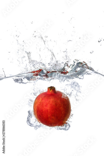 Falling of pomegranate into water on white background