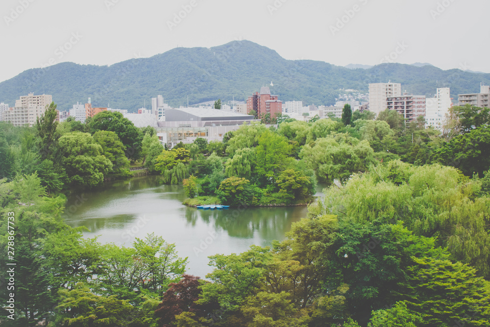 Tropical view of Nakajima Park (Koen) with cityscape of Sapporo City in the background at Hokkaido, Japan
