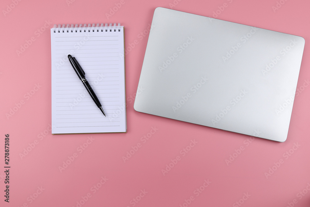 Laptop and pen notepad on Pink color background Laptop and pen notepad on Pink color background